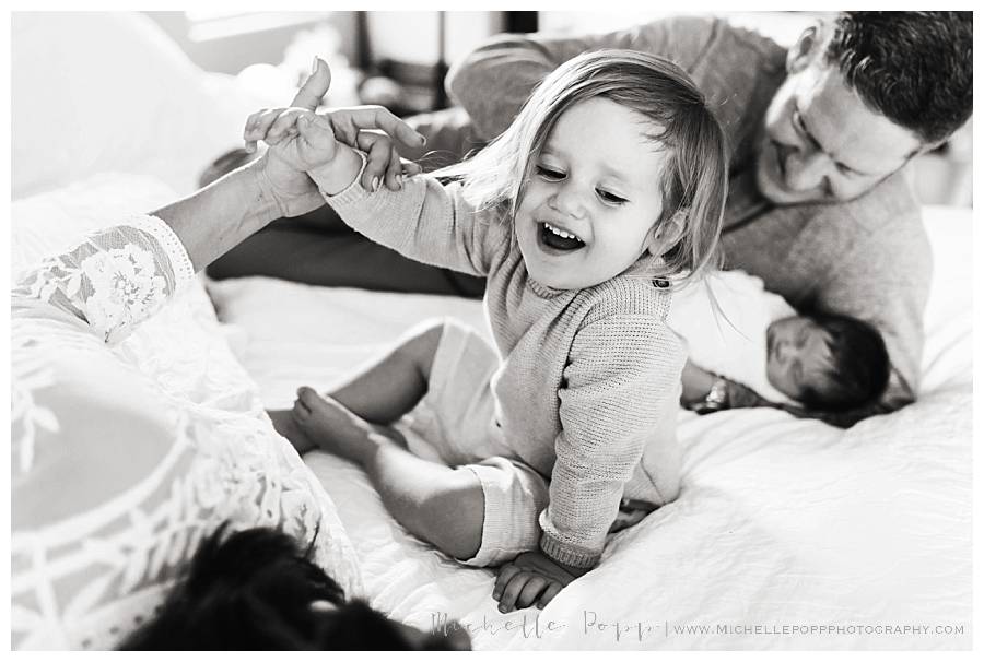 mom and dad playing with kids on bed