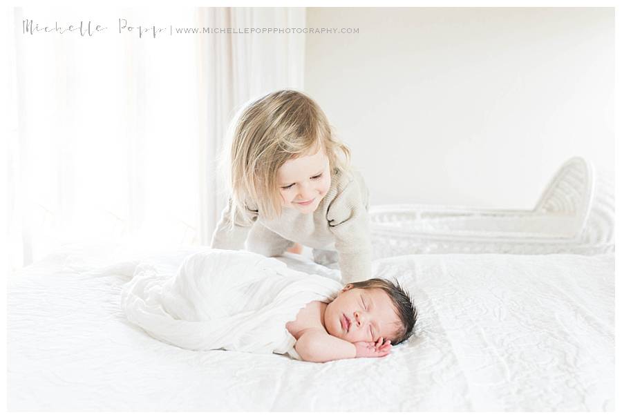 toddler looking down at new baby sibling