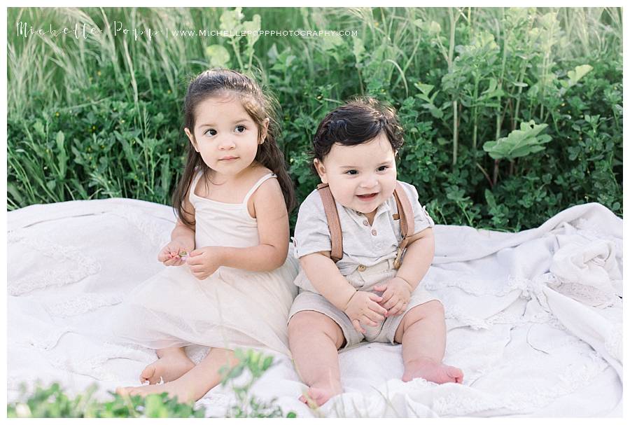 toddler girl and baby boy sitting on blanket