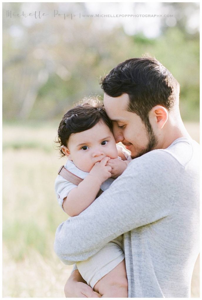 dad snuggling baby boy in arms