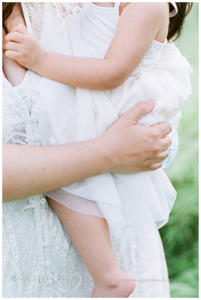 close up of mom holding toddler girl legs