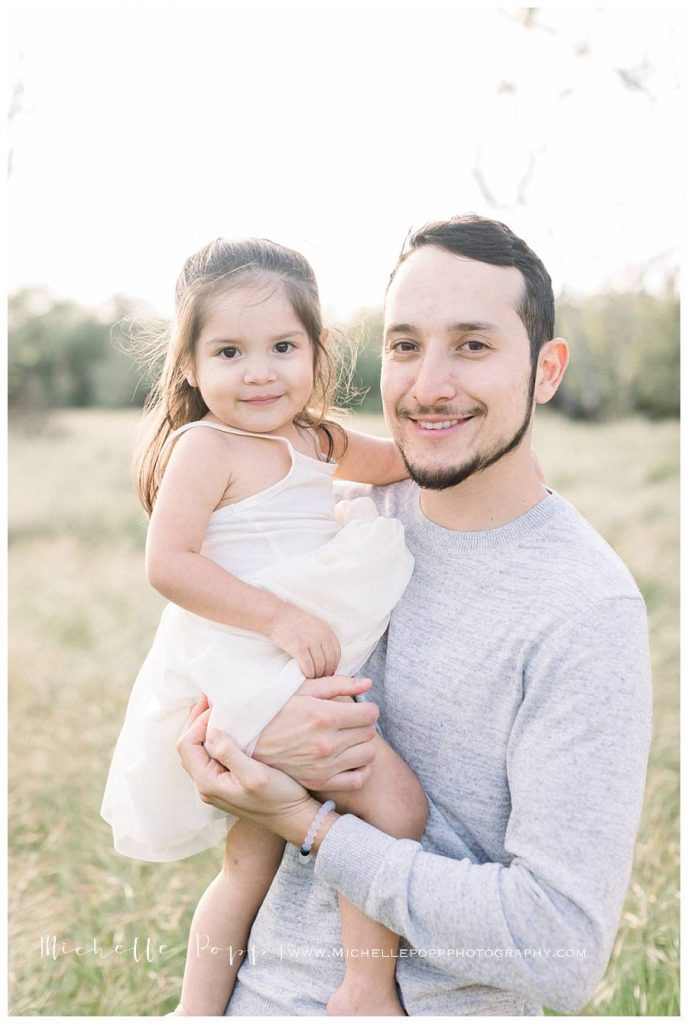 dad holding daughter and smiling