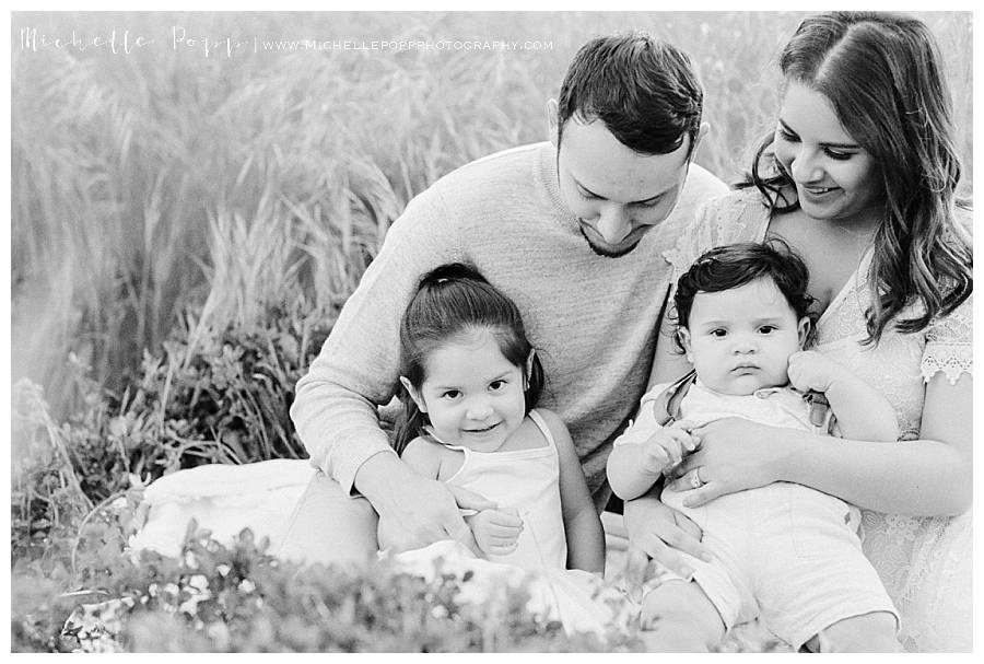 family of four sitting on blanket in field