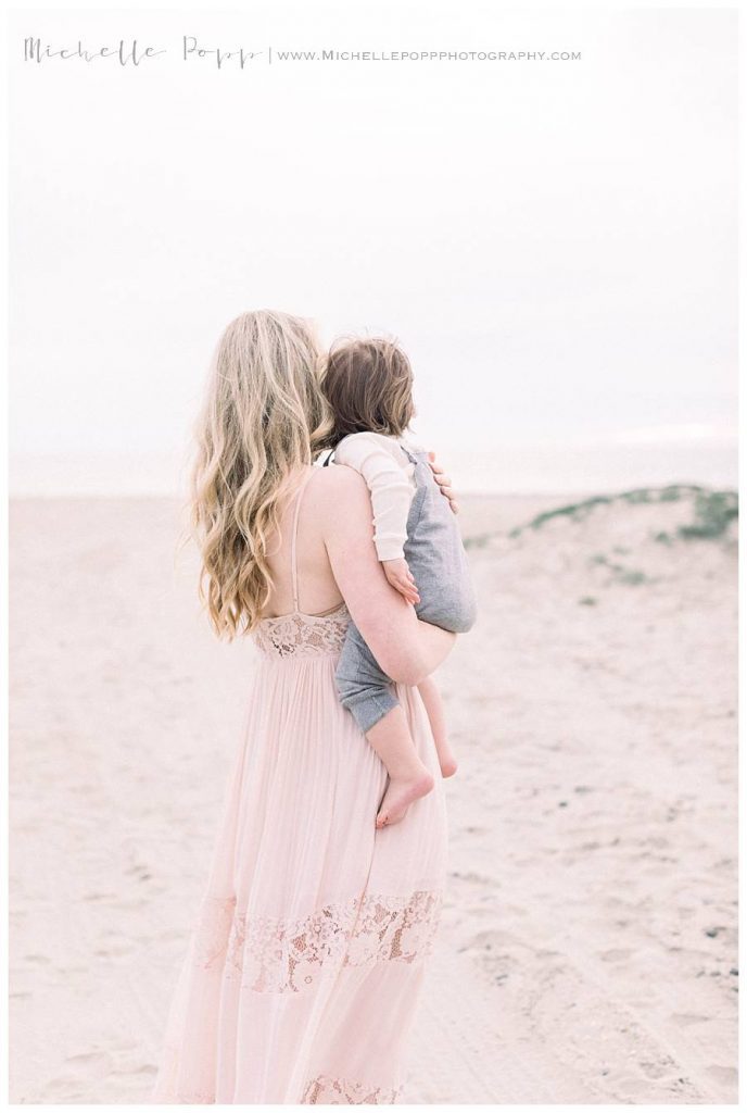 mom looking out onto water holding son