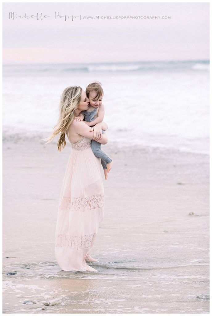 mom holding baby boy by the water