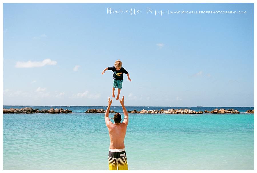 dad throwing son into air at beach