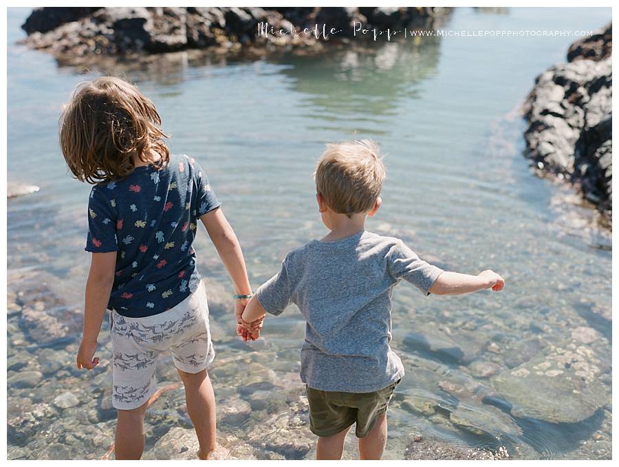 boys holding hands by the water