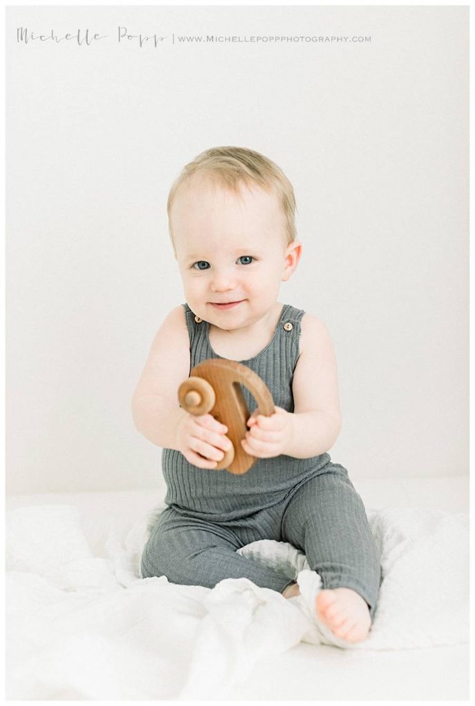 toddler boy sitting on bed with toy