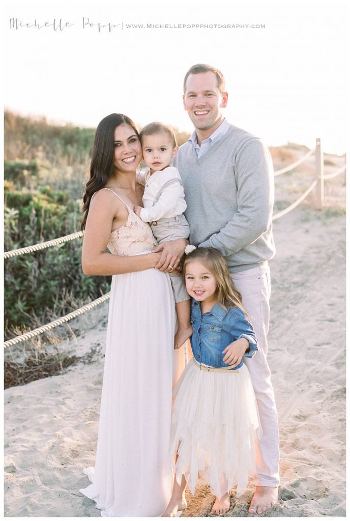 family of 4 standing on sand