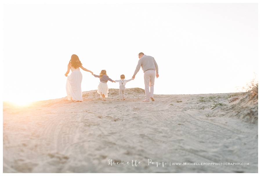 family of four holding hands walking