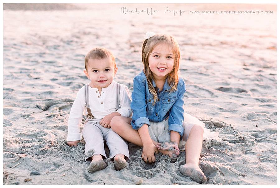 little boy and girl sitting on sand