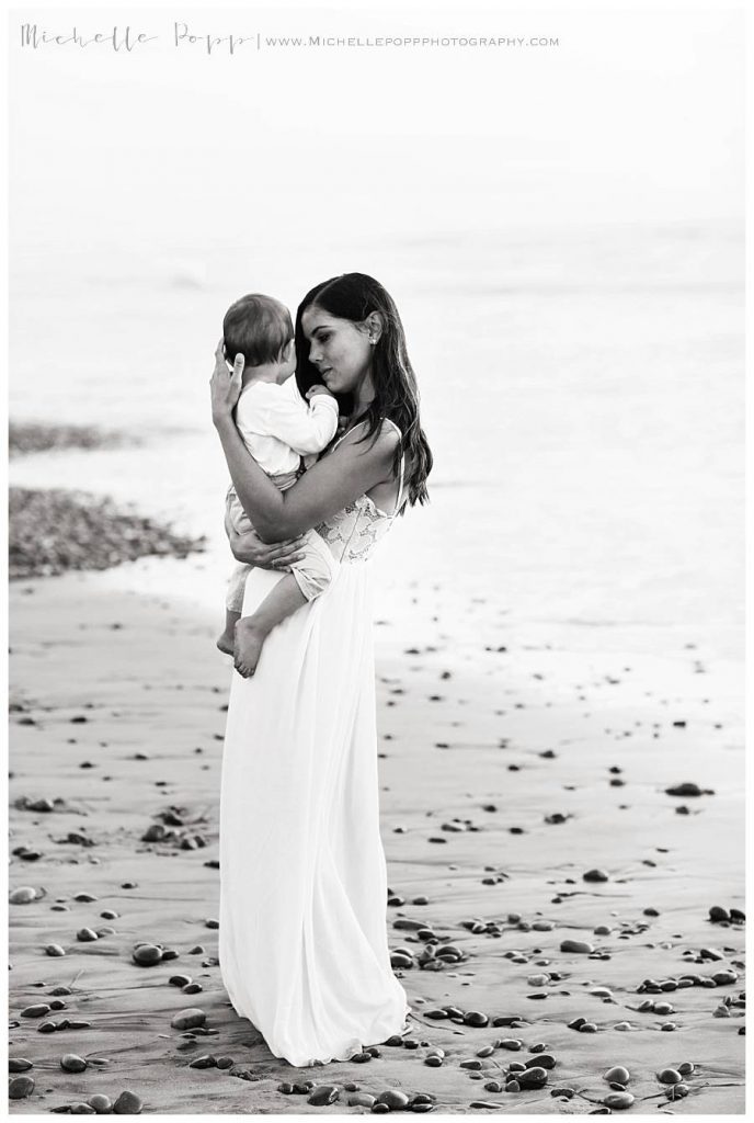 mom holding son in arms at the beach