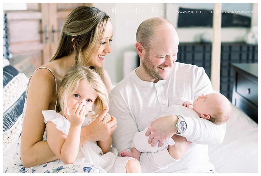 family of four sitting on bed