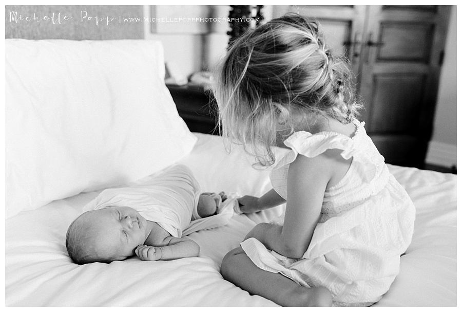 little girl looking at baby on bed