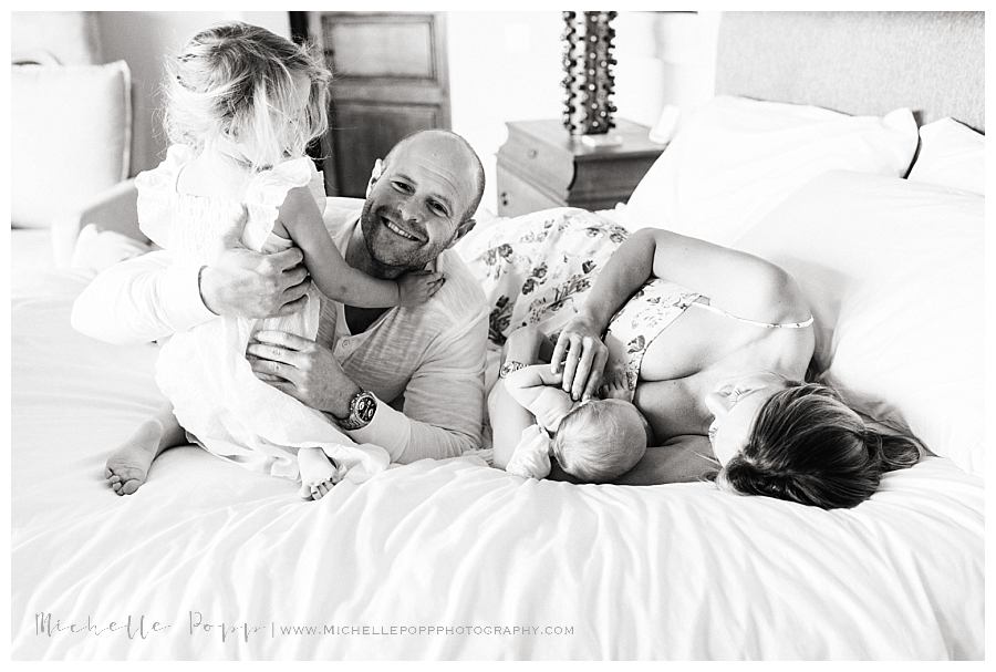 family snuggling together on bed