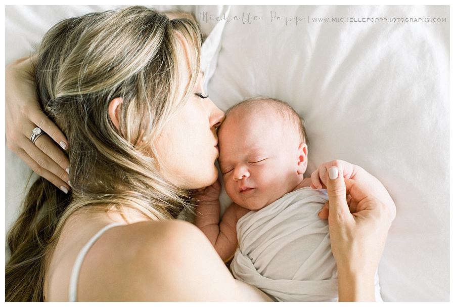 mom kissing newborn baby's forehead