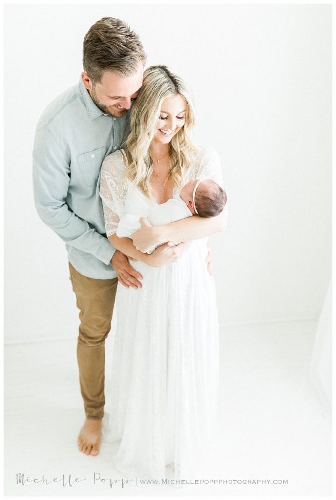 mom and dad looking down at new baby girl Intimate newborn photography