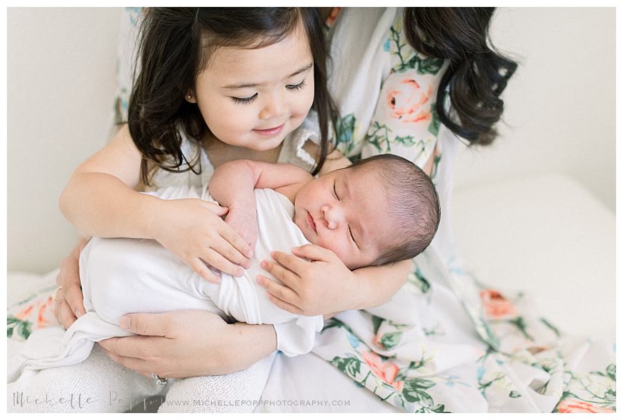 toddler girl holding newborn baby