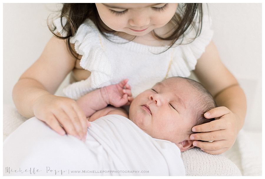 toddler girl holding new baby