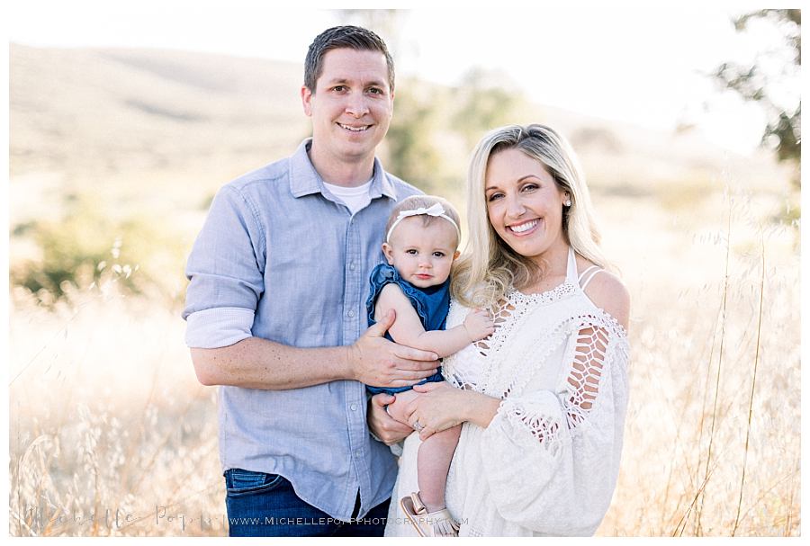 mom dad and baby girl looking at camera