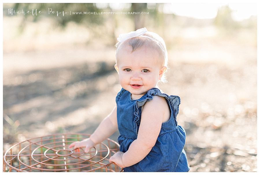 baby girl standing up holding onto basket