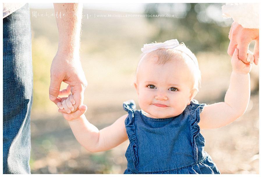 baby girl holding mom and dad's hands