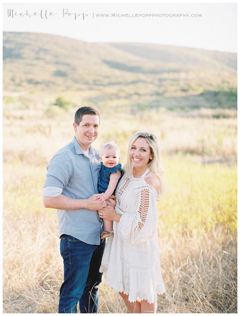 mom dad and daughter in a field