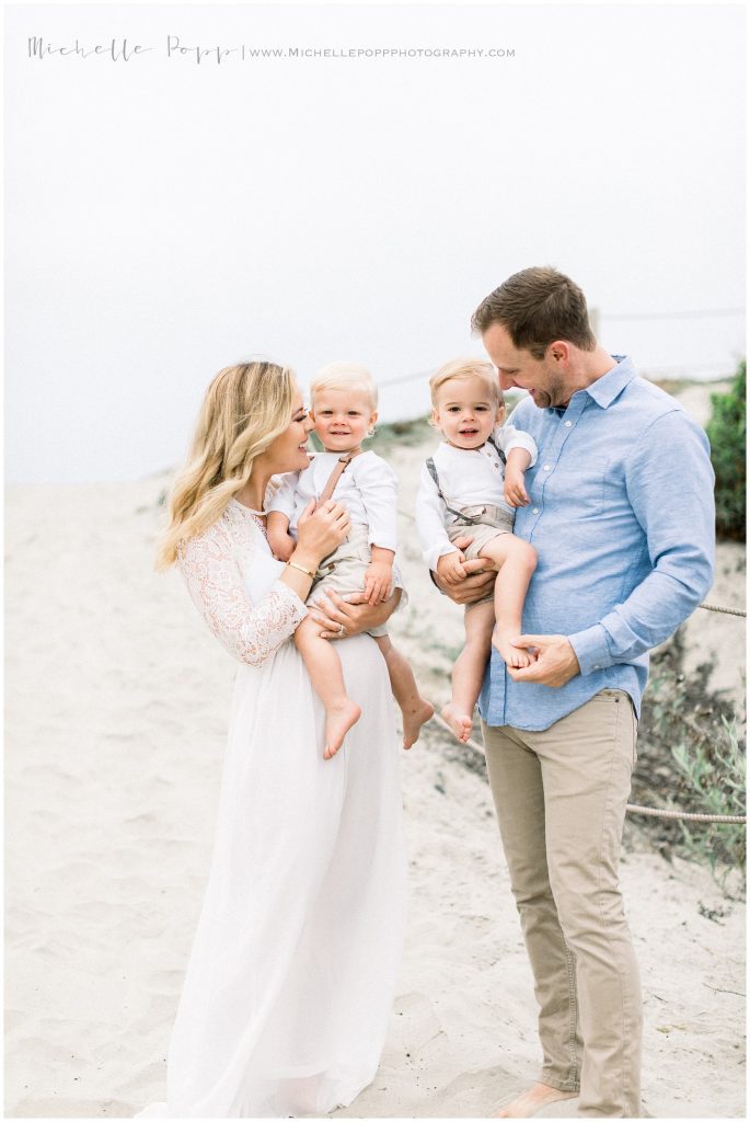 mom and dad holding boys on the beach 