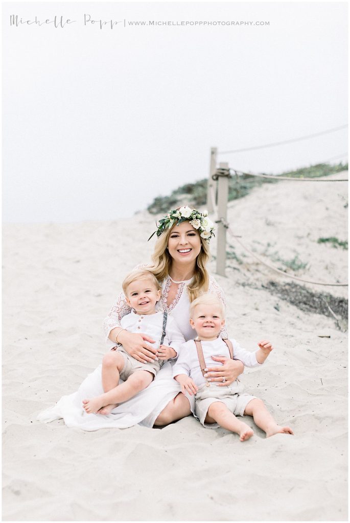 mom holding twin boys on the beach