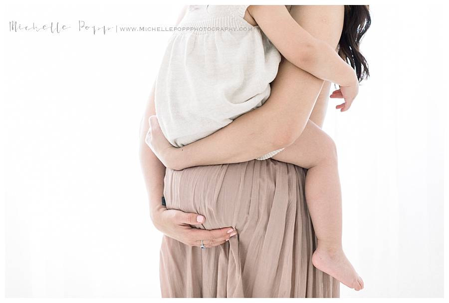 pregnant mom holding daugher