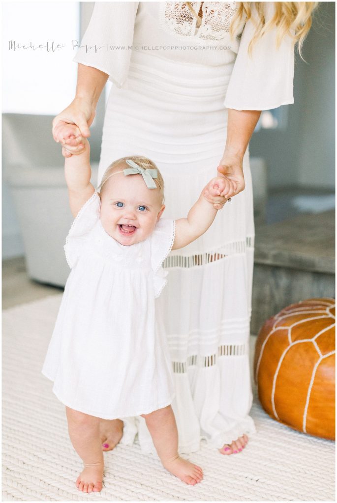 baby girl holding onto mom and smiling