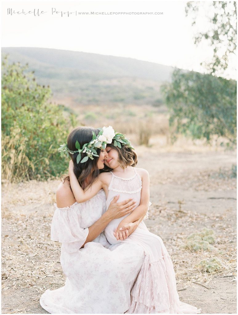 daughter and mama sitting in a field snuggling