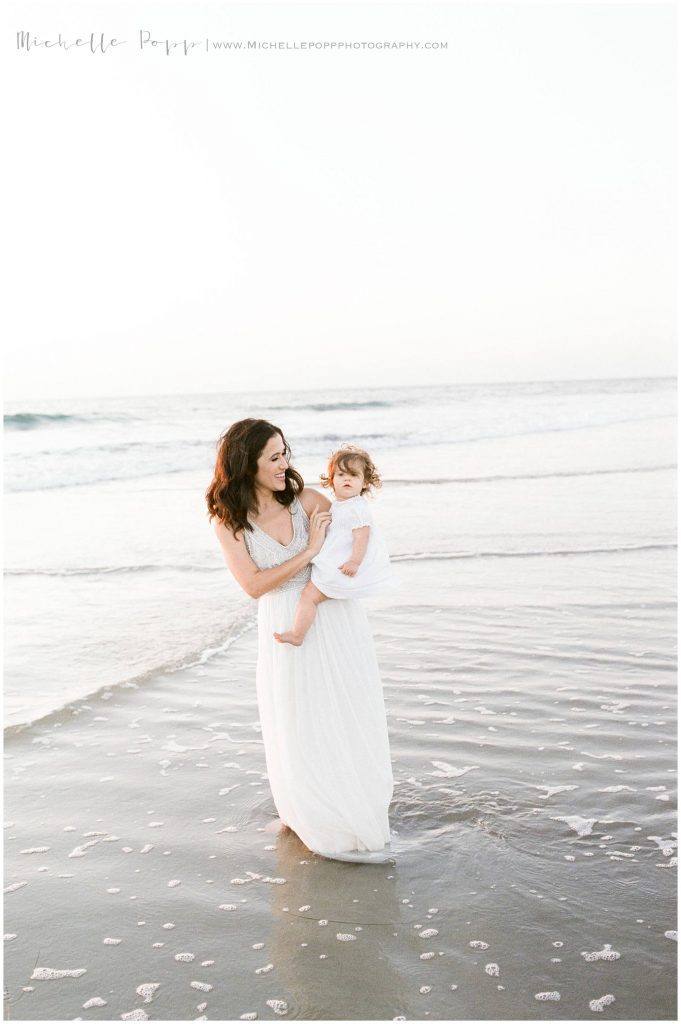 mom walking along ocean with daughter