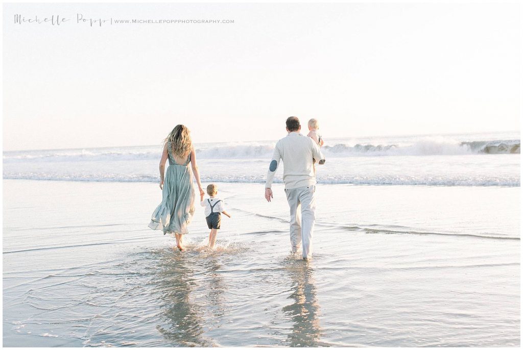 family walking along water at carlsbad beach