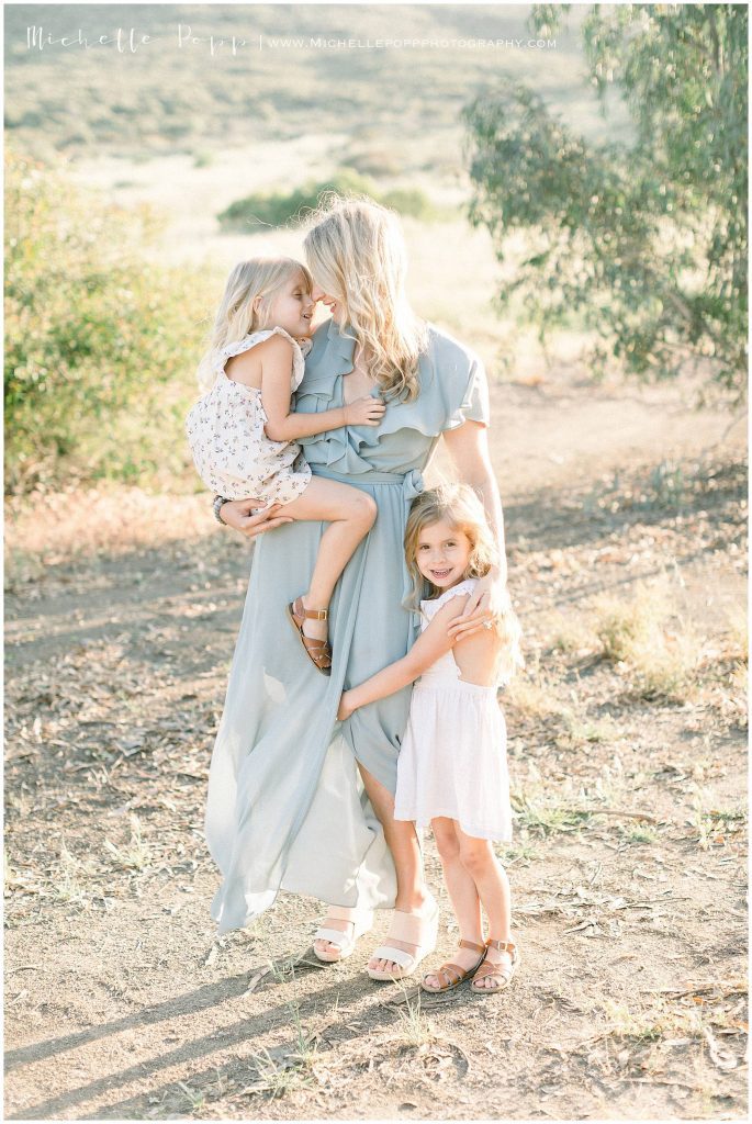 mom in field snuggling two girls