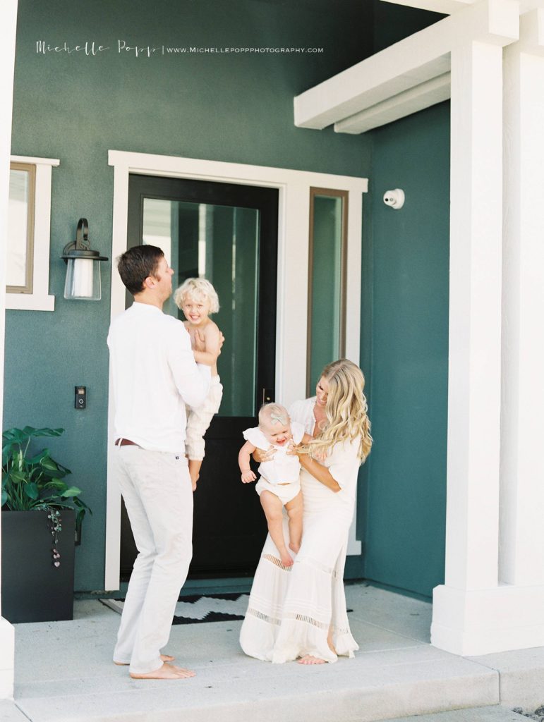 mom and dad throwing babies in air in front of Encinitas home