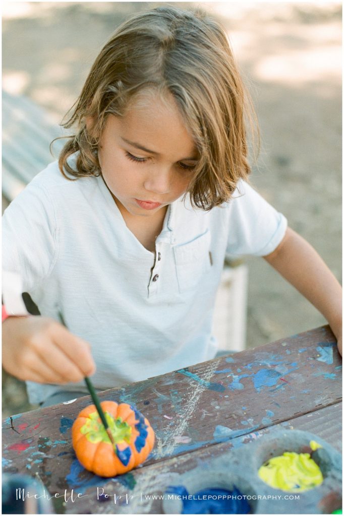 little boy in white shirt painting pumpkins Fall Activities in San Diego  