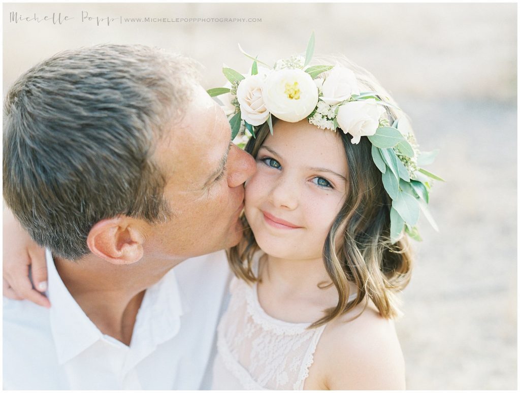 dad kissing daughter on the cheek