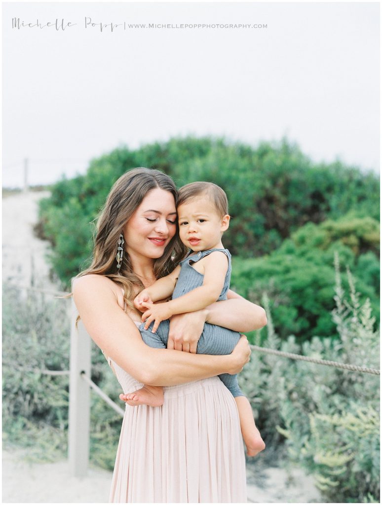 mom in pink dress holding little boy