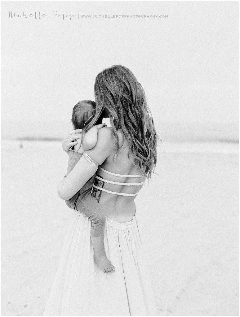 mom facing ocean with little boy on hip