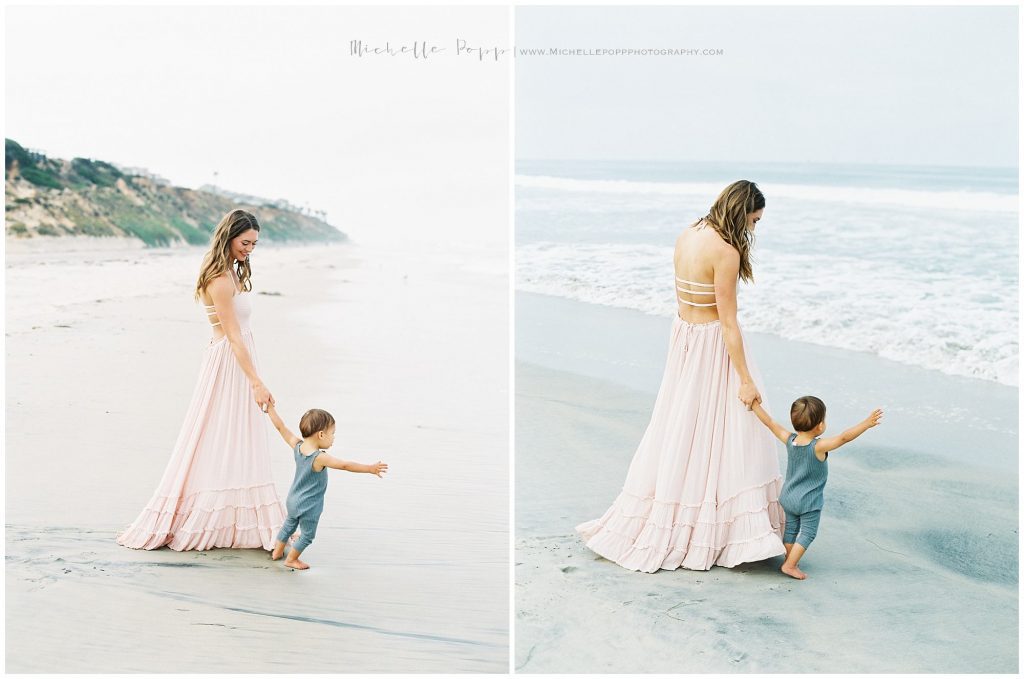 mom and toddler boy holding hands at the beach