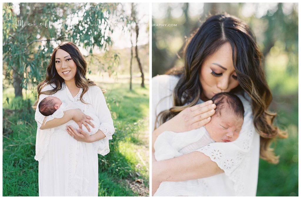 mom smiling at camera with newborn baby in arms in field