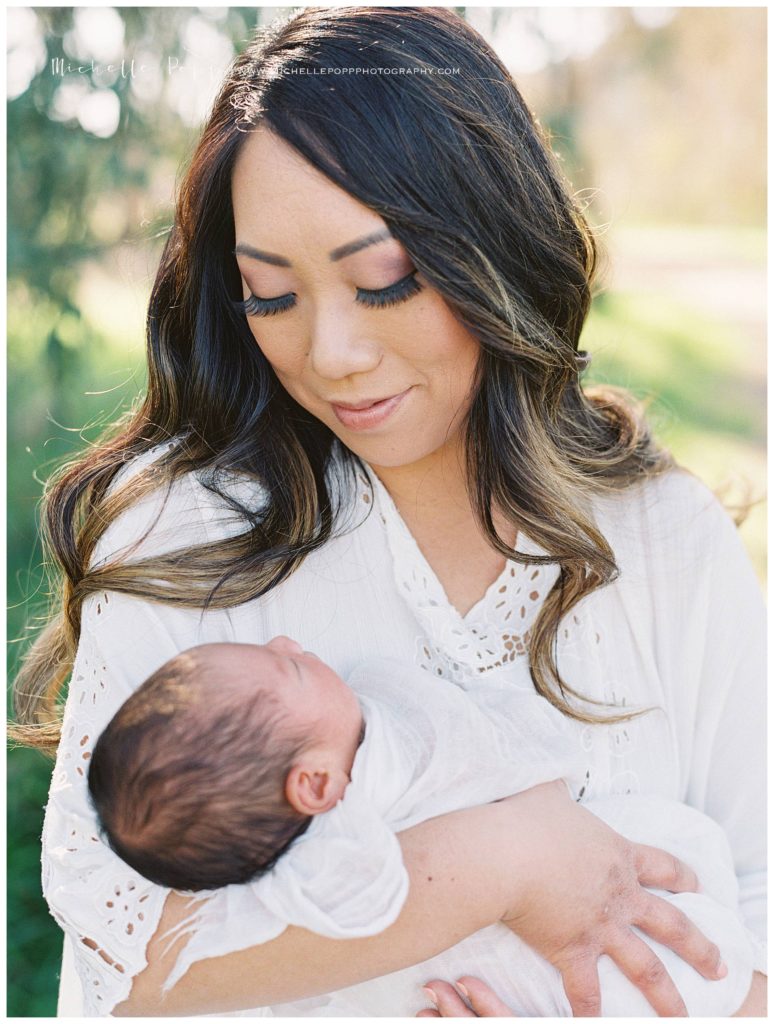 close up of newborn baby in mom's arms outdoors