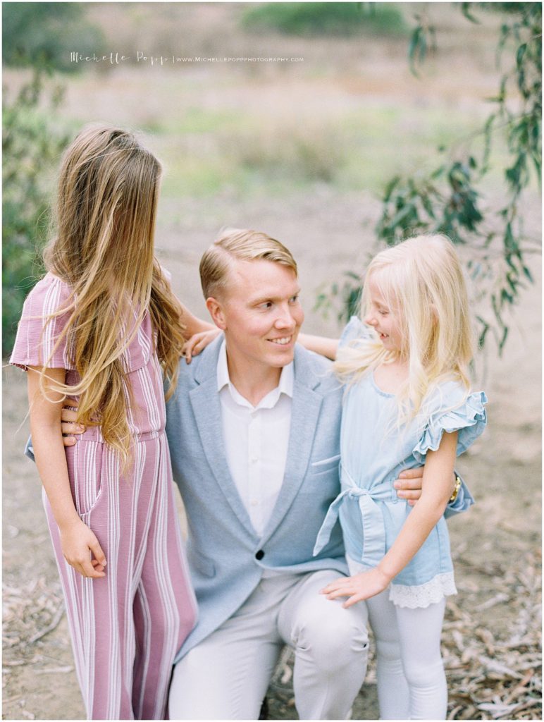 dad smiling with his two daughters