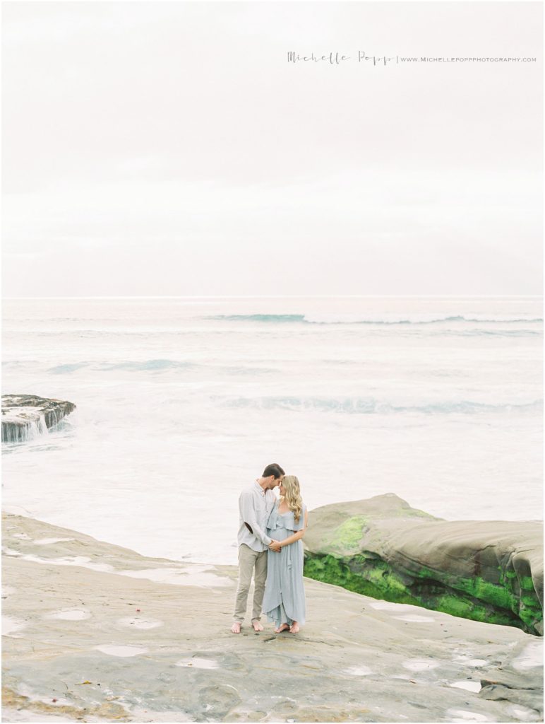 mom and dad standing forehead to forehead on cliffs