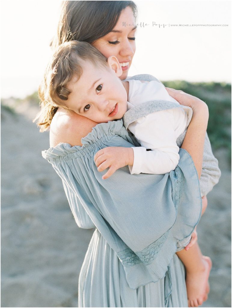 Mom snuggling son on the beach 