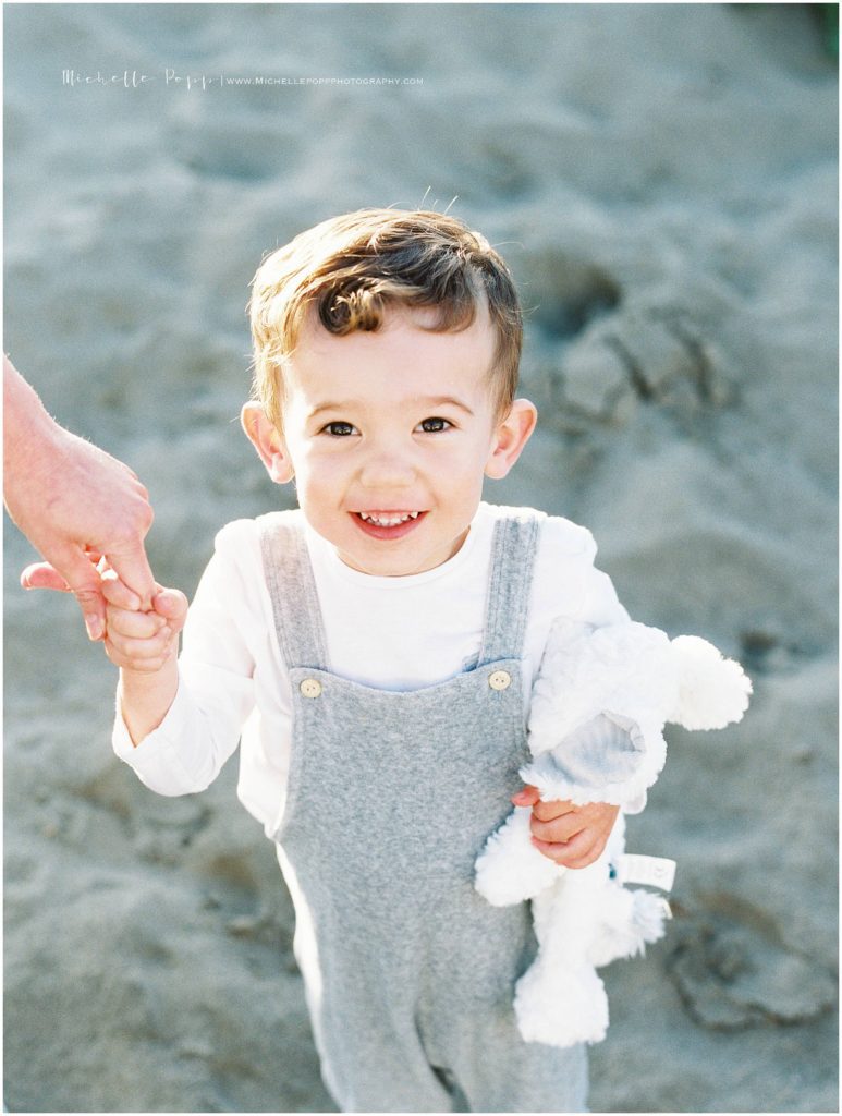 boy holding stuffed bunny and smiling at camera