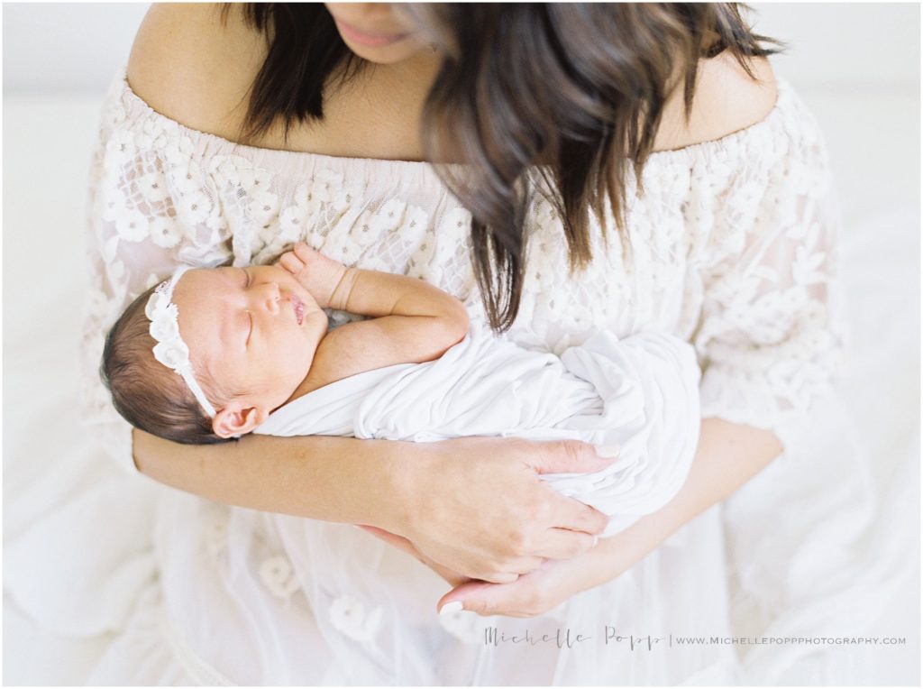 mom snuggling baby girl in her arms 