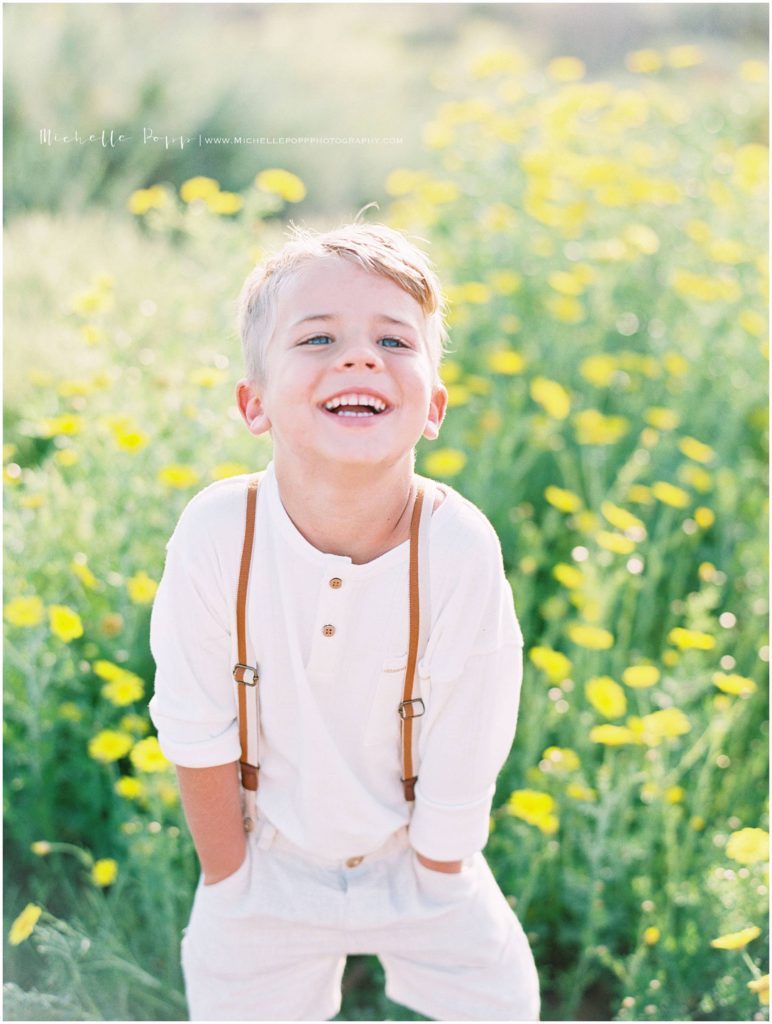 little boy laughing in field of San Diego wildflowers