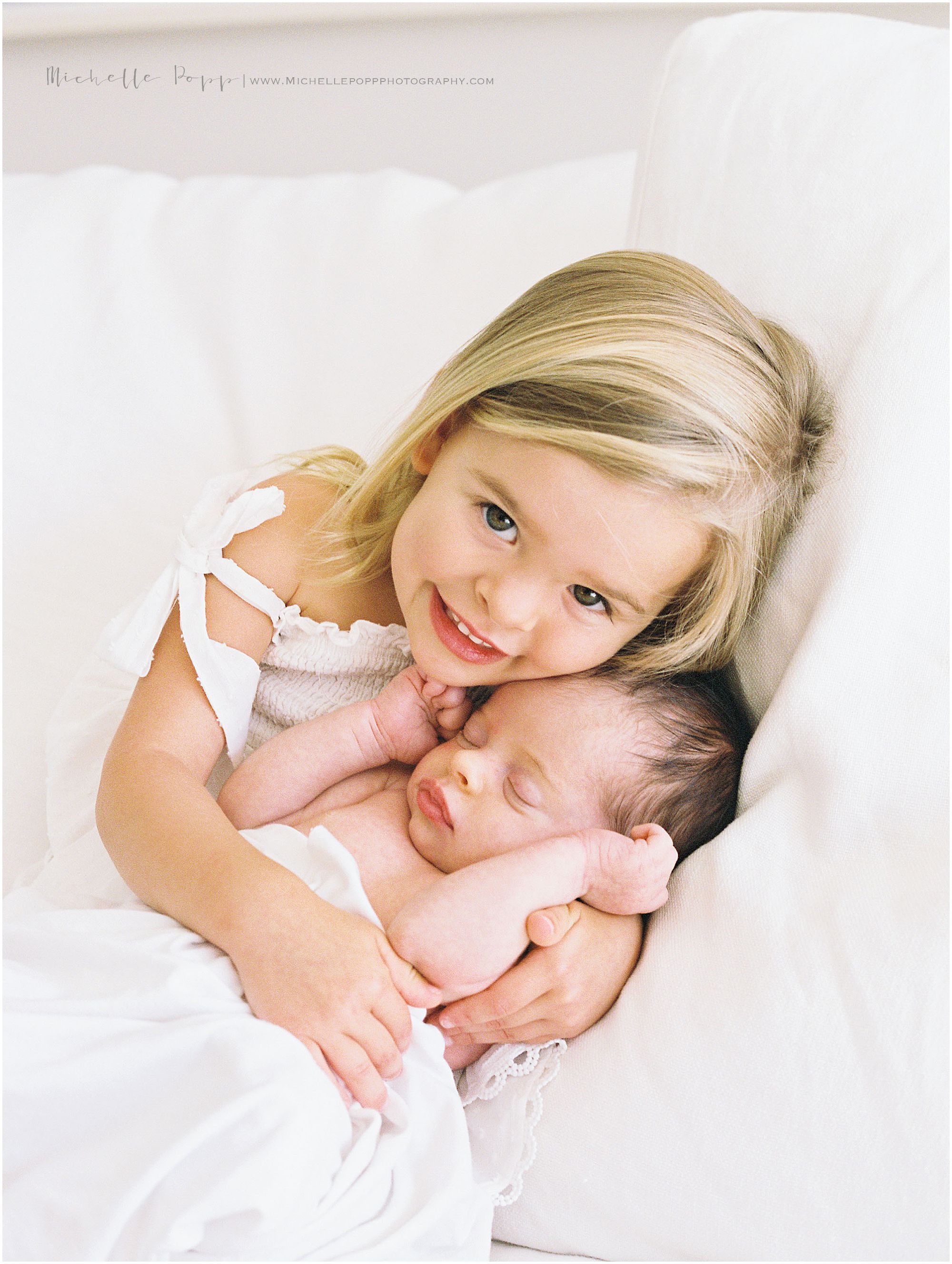 big sister holding her new baby sister 